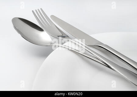 Spoon, fork and knife on white empty plate. On white background Stock Photo