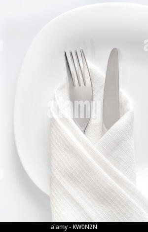 Fork and knife on white plate. Table setting close up, top view Stock Photo