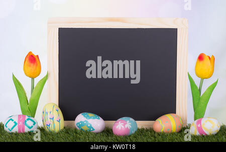 Colorful Easter eggs and tulips with a blank chalk board for copy space Stock Photo