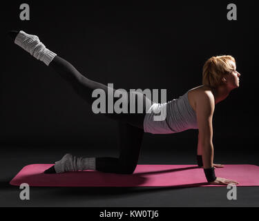 Young woman practicing yoga, Vyaghrasana / Tiger Pose Stock Photo