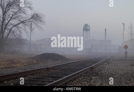 Train tracks lead to a factory warehouse and water tower as downtown Port Huron is enveloped in a thick fog. Port Huron, Michigan