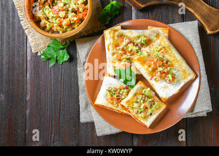 Traditional Mexican dish - chimichanga. Corn cake with minced meat, pepper, onion, garlic, oregano, zira and guacomole sauce from avocado Stock Photo