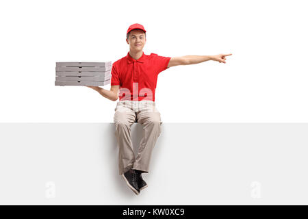 Teenage pizza delivery boy sitting on a panel and pointing isolated on white background Stock Photo