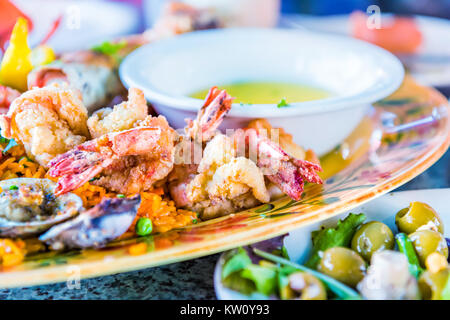 Macro closeup of fried seafood on plate with garlic butter bowl, shrimp, olive salad, rice on platter Stock Photo