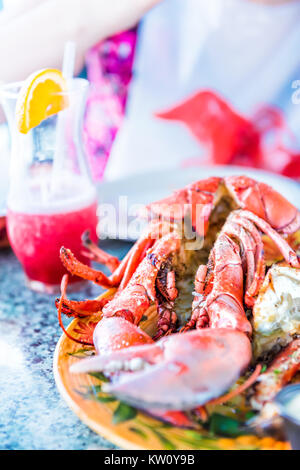 Macro closeup of whole lobsters in shell and seafood platter on plate with red or pink alcoholic drink Stock Photo