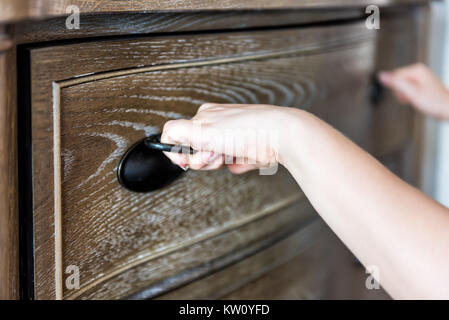 Closeup of wooden chest drawer in bedroom with natural light in staging home, house apartment model, and woman's hands opening it Stock Photo