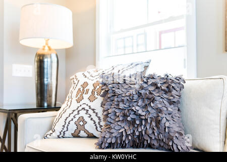 Closeup of two pillows on couch or sofa by bright window in modern apartment, house or home with staging of large beige, neutral white colors, lamp Stock Photo