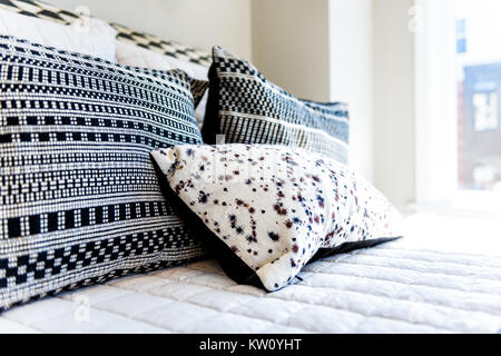 Closeup of new bed comforter with decorative pillows, headboard in bedroom in staging model home, house or apartment Stock Photo