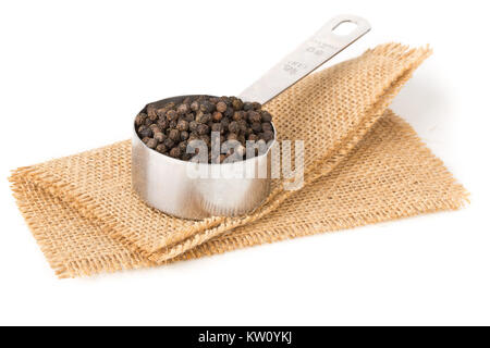 Raw, natural, unprocessed black pepper peppercorns in measuring cup on white background Stock Photo