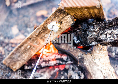 Closeup of one white marshmallow caramelizing on fire showing detail and texture by campground campfire grill in outdoor park with flame, smoke Stock Photo