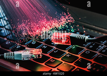 network cable closeup with fiber optical background, color fiber optical background with notebookk, Fiber optics lights abstract background Stock Photo