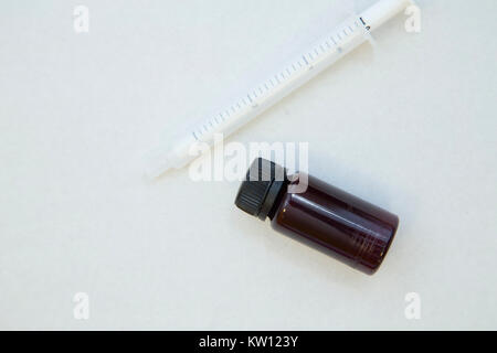 Veterinary and animal healthcare concept. Curing pets. A white plastic syringe and a bottle with cure of dark glass, close up, white background.Space  Stock Photo