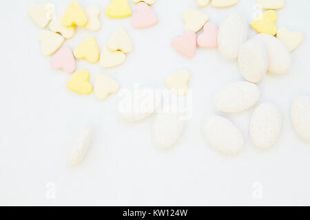 Veterinary and animal healthcare concept. Curing pets. A white background with pink and yellow heart shaped pills and white oval pills, close up. Spac Stock Photo