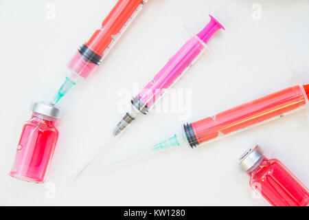 Veterinary and animal healthcare concept. Curing pets. Colorful syringes and glass ampouls with red cure on a white surface, close up. Space for your  Stock Photo