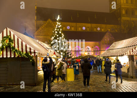 Traditional Christmas street market in Latvia on cold winter day, magnificent church in background. People are eating, drinking, having fun. Stock Photo