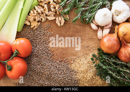 Healthy food frame with fresh vegetables, herbs and grains on rustic wooden background viewed from above. Stock Photo