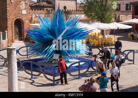 Tourists posing in front of the spectacular 'Comet Glass Star' sculpture on the island of Murano, Venice Stock Photo