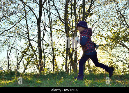 Laughing Happy little girl running in sunlight on autumn meadow. Stock Photo