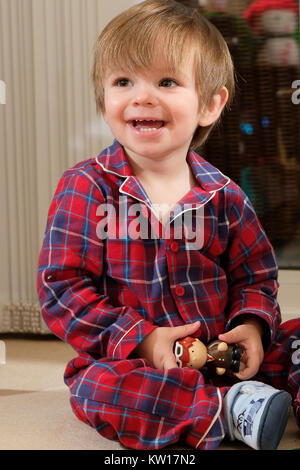 Happy toddler boy in pajamas playing with toy and smiling happily Stock Photo
