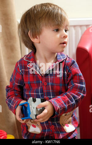 Young, toddler boy in pajamas playing with toy car Stock Photo