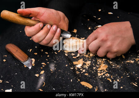 Man's hands working suit carving a wooden spoon with a knife Stock Photo