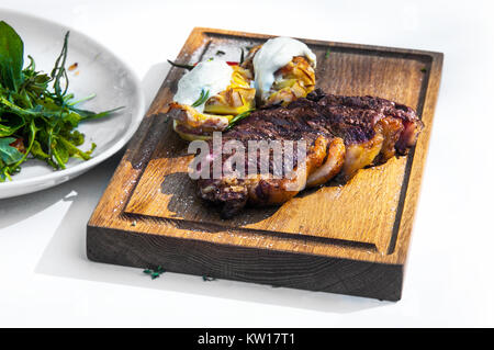 Meat dish. Pieces of roasted meat, parsley, sauce, red pepper, lie on a wooden board. lettuce leaves. Isolated on white background Stock Photo