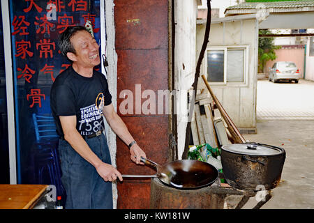 Cook in Taicang, China. A small street-front restaurant that I often ate meals at in the evenings. The cook was always happy to cook a wonderful meal. Stock Photo