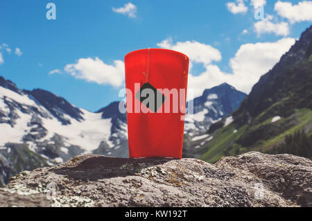 Orange plastic mug with strong tea and tea bag on a snowy winter background. Stock Photo