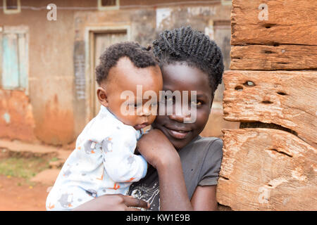 Lugazi, Uganda. June 09 2017. A young African girl holding her baby sister or her child in her arms. Stock Photo