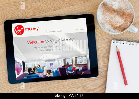 The Virgin Money website on an iPad tablet device which rests on a wooden table beside a notepad and pencil and a cup of coffee (Editorial only) Stock Photo