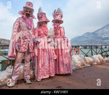 Annecy, France- February 23, 2013: A group of three people disguised in beautiful pink costumes pose near the Annecy Lake during a Venetian Carnival.  Stock Photo