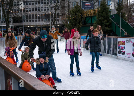 Edinburgh, Scotland, United Kingdom, 30th December 2018. Families with small children enjoying the New Year weekend ice skating in St Andrew Square. A parent pushes a child in a seal ice skating aid Stock Photo