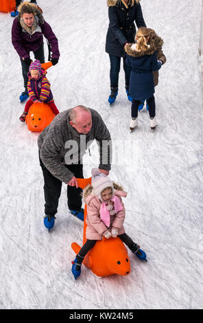 Edinburgh, Scotland, United Kingdom, 30th December 2018. Families with small children enjoying the New Year weekend ice skating in St Andrew Square. A parent pushes a child in a seal ice skating aid Stock Photo