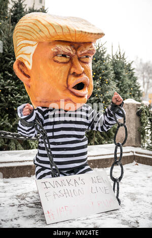 New York, USA, 30 Dec 2017.  A protester wearing a mask mocking a chained US President Donald Trump on a jail uniform performs in front of New York city's Plaza Hotel .  The sign reads (Trump's daughter) 'Ivanka's New Fashion Line' #Impeach Trump. Demonstrators braved a snowstorm to demand Trump's impeachment. Photo by Enrique Shore/Alamy Live News Stock Photo
