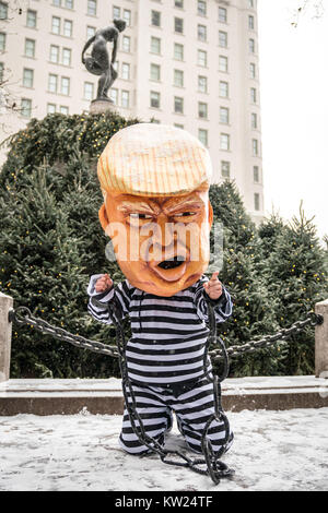 New York, USA, 30 Dec 2017.  A protester wearing a mask mocking a chained US President Donald Trump on a jail uniform performs in front of a statue of Roman godess Ponoma next to New York city's Plaza Hotel .  Demonstrators braved a snowstorm to demand Trump's impeachment. Photo by Enrique Shore/Alamy Live News Stock Photo