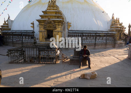 Man and street dog sitting at Swayambhunath temple in Kathmandu, Nepal Stock Photo