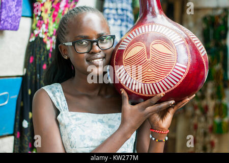 Craft stall proprietor holding decorated gourd, Handicraft Centre, Entebbe, Wakiso, Uganda Stock Photo