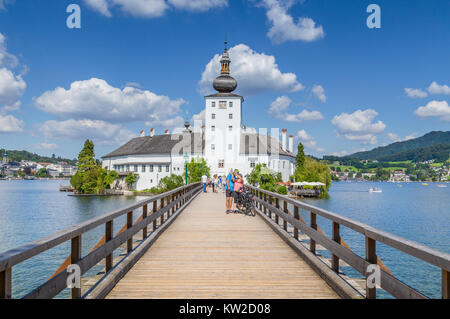 Tourist couple taking a selfie in front of famous Schloss Ort on a sunny day with blue sky and clouds in Gmunden, Salzkammergut region, Austria Stock Photo