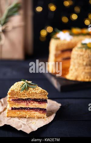 Piece of Christmas Honey cake with rosemary and oranges on black background. Stock Photo