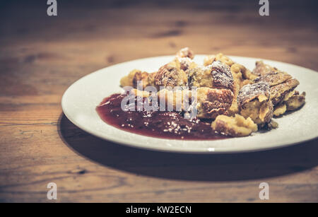 Traditional Austrian Kaiserschmarrn pancakes dessert served with plum compote  on rustic wooden table in retro vintage Instagram style filter effect Stock Photo
