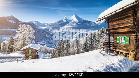 Panoramic view of beautiful winter wonderland mountain scenery in the Alps with traditional mountain chalets on a cold sunny day with blue sky Stock Photo