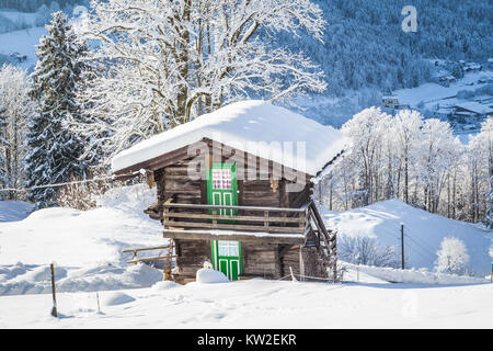 Beautiful view of traditional wooden mountain chalet embedded in scenic white winter wonderland mountain scenery in the Alps on a cold sunny day Stock Photo