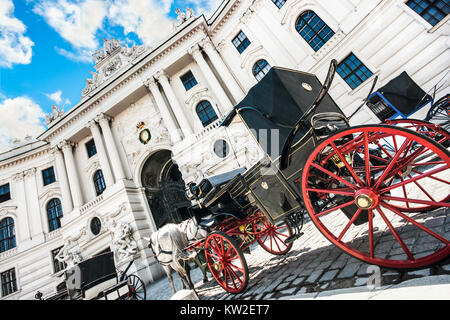 Wide-angle view of famous Hofburg Palace with traditional horse-drawn Fiaker carriages on a sunny day in Vienna, Austria Stock Photo