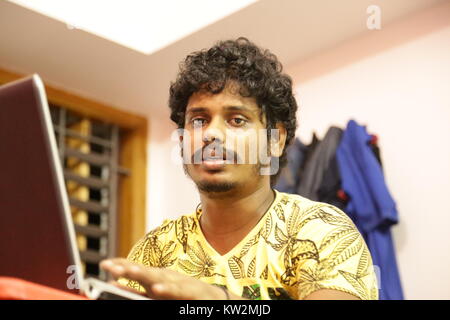 Chennai, India - May 20, 2016: Young man using laptop at desk Stock Photo