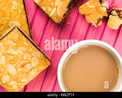 Cherry Bakewell Tarts With a Cup or Mug of Tea or Coffee Against a Pink Background Stock Photo