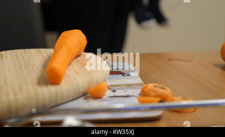 Fresh clean carrots with knife on heart shaped wooden cutting board. Stock Photo