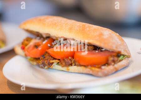 close up of tandoori sandwich with tomatoes on a white plate Stock Photo