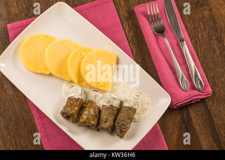 Grape leaf rolls with sour cream sauce on a traditional background Stock Photo