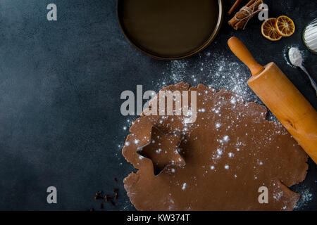 Christmas gingerbread star cookie cutter on gingerbread dough with flour, teaspoon of flour, cinnamon sticks, dried orange slices and rolling pin. Stock Photo