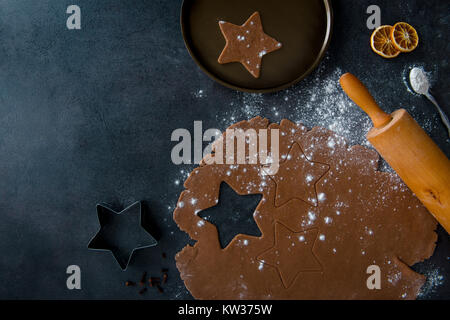 Christmas gingerbread star cookie cutter, gingerbread dough with cookie cutout, star shaped cookie on plate, teaspoon of flour, dried orange slices. Stock Photo